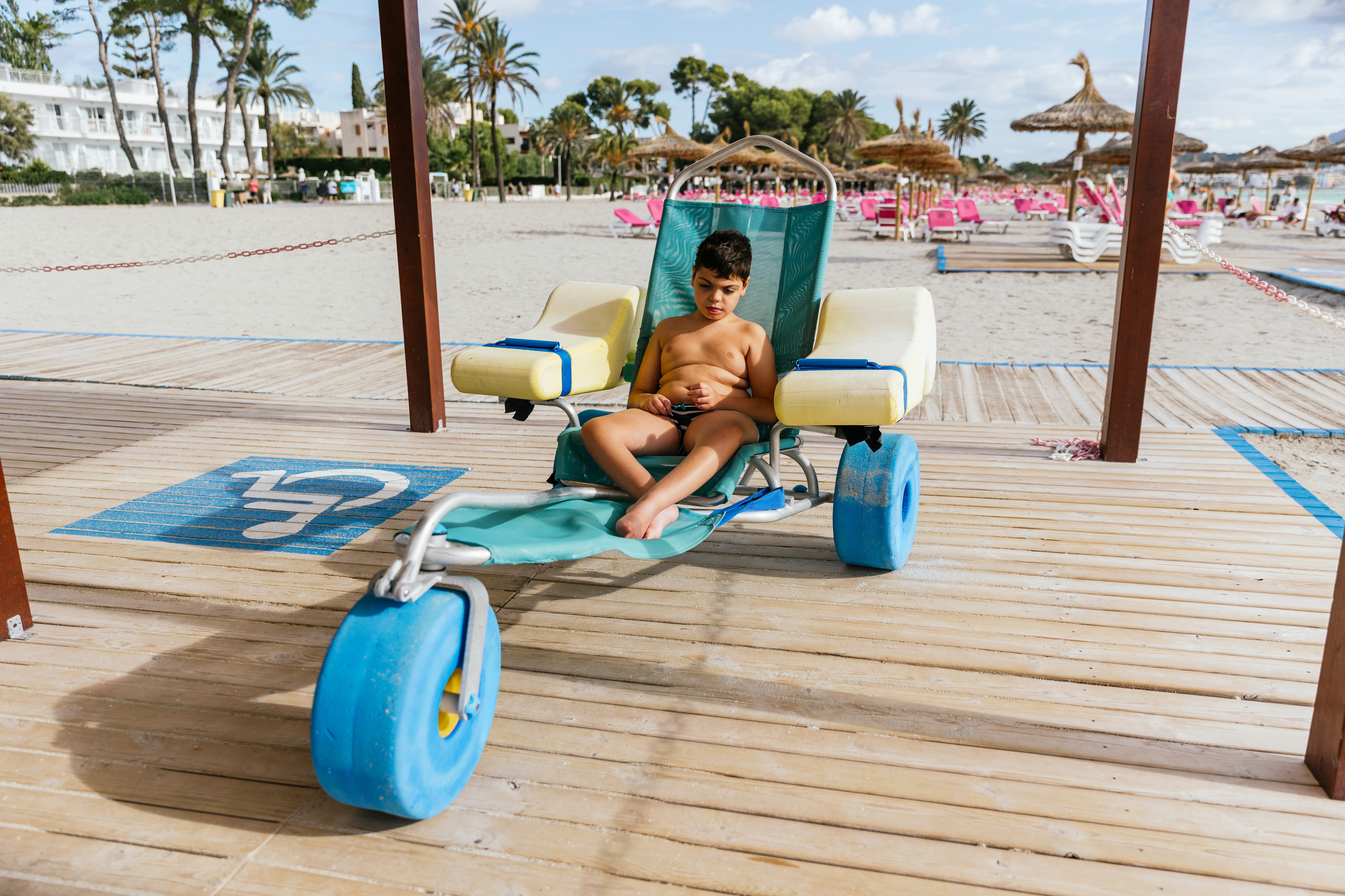 Child with cerebral palsy relaxing on a floating wheelchair, enjoying a sunny beach vacation in alcudia