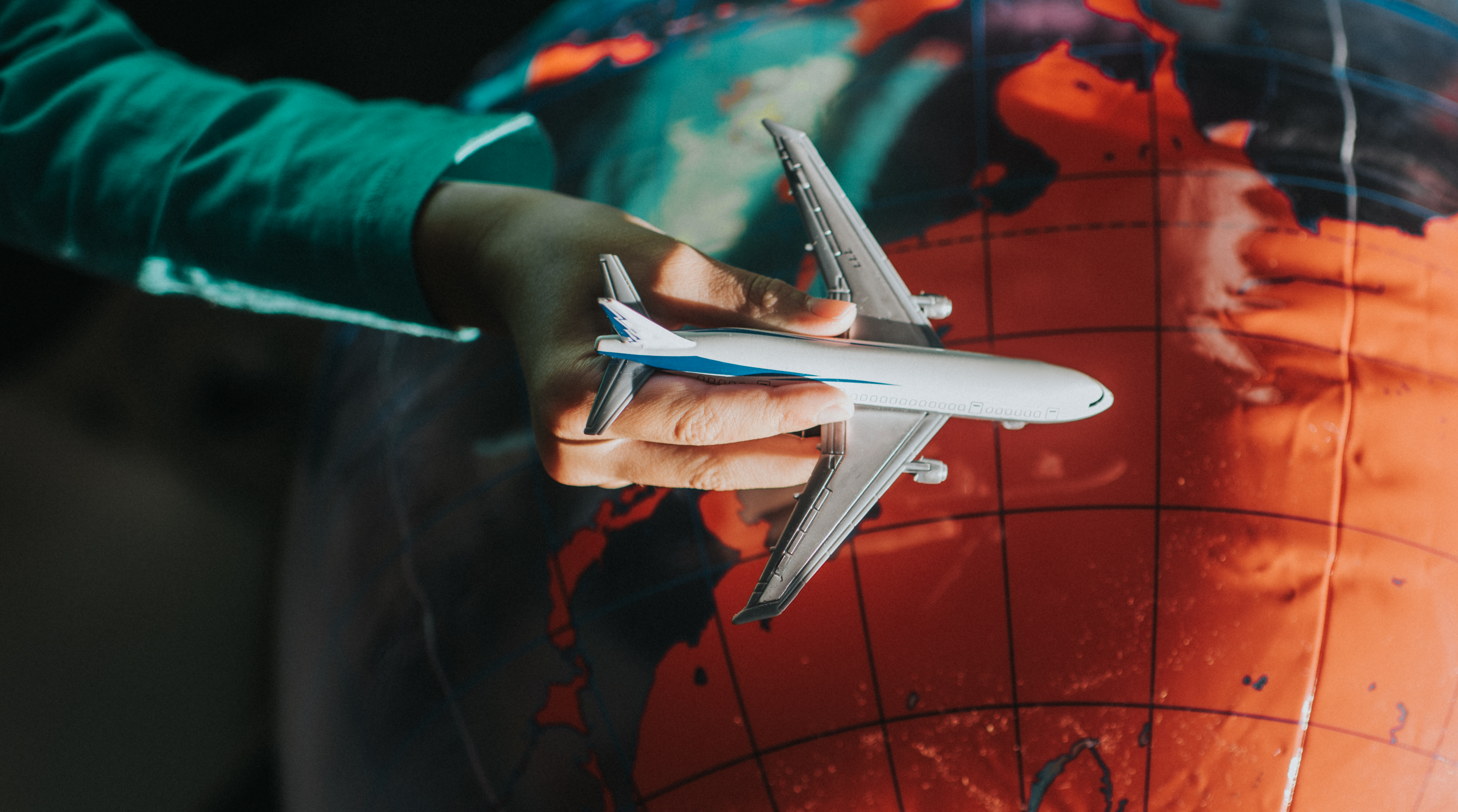 Child flying a toy plane around an inflatable globe. Conceptual with space for copy.